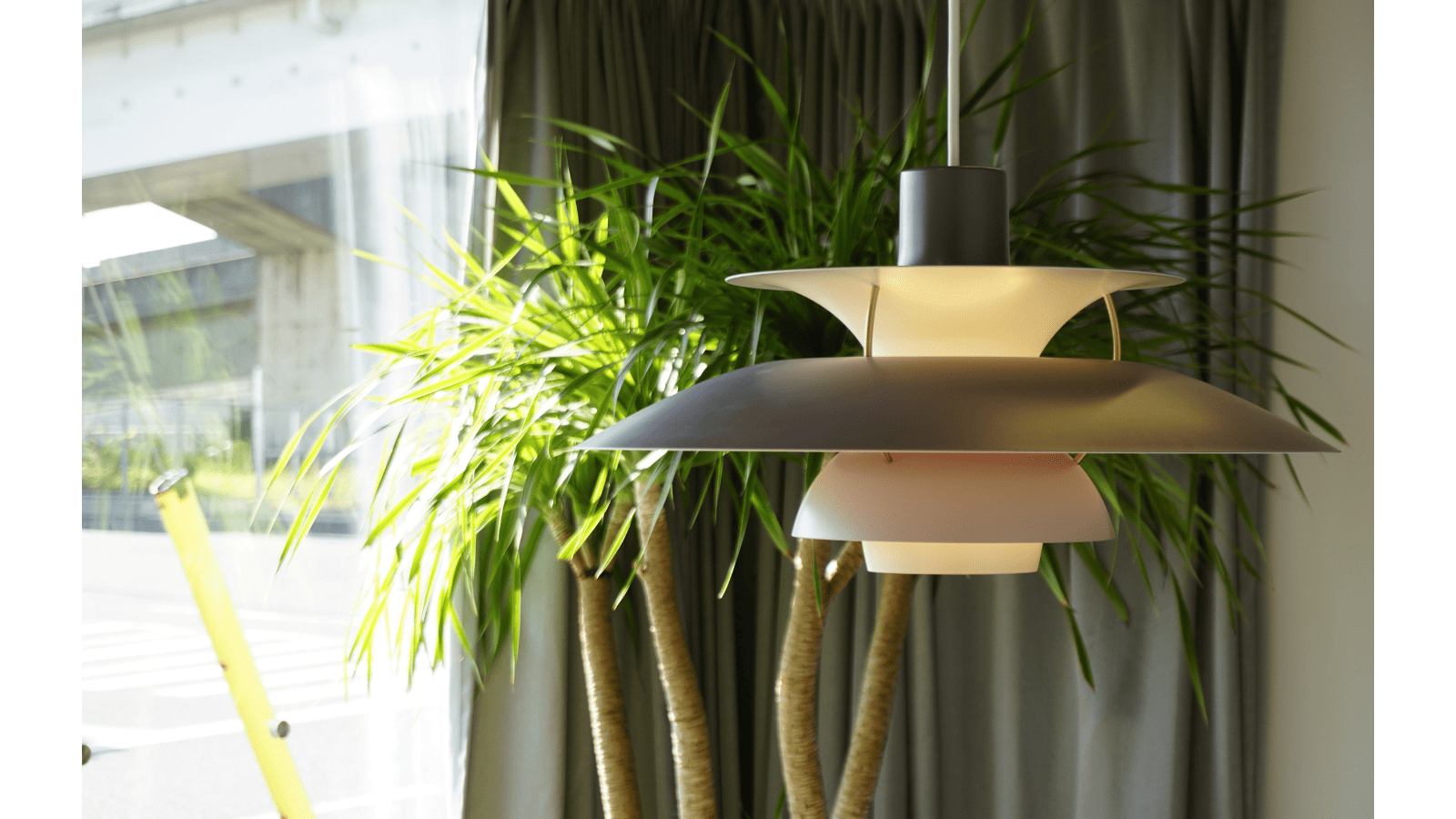 大きな観葉植物を背景に、光を受けて浮かび上がるルイスポールセンのペンダントライト「PH5」の美しいシルエット
